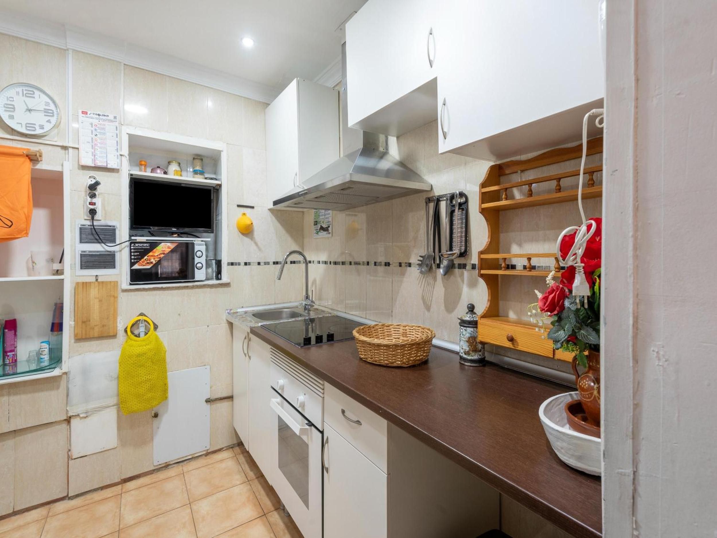 Une cuisine avec des meubles blancs, un four à micro-ondes, une cuisinière et un évier.