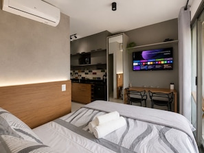 A modern hotel room with a bed, a TV, a desk, and a kitchenette. - On Paulista 817 (Vila Mariana)