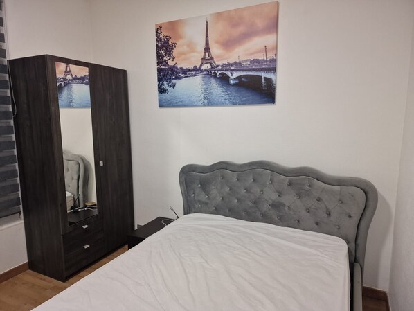 A bedroom with a bed, a wardrobe, and two paintings of the Eiffel Tower. - Vrbo Property (Nanterre)