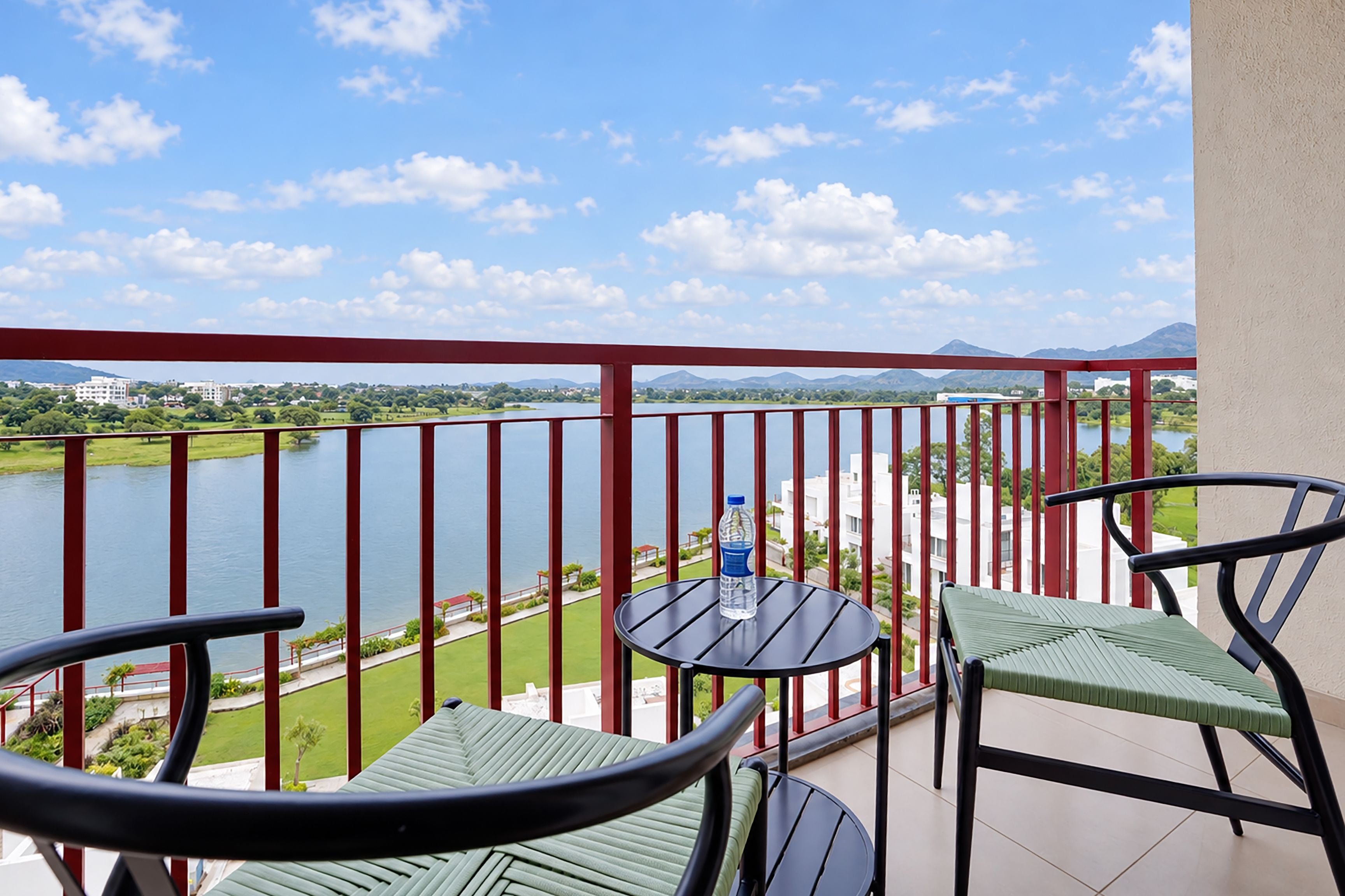 A balcony with a table and chairs, overlooking a river and a distant mountain range.