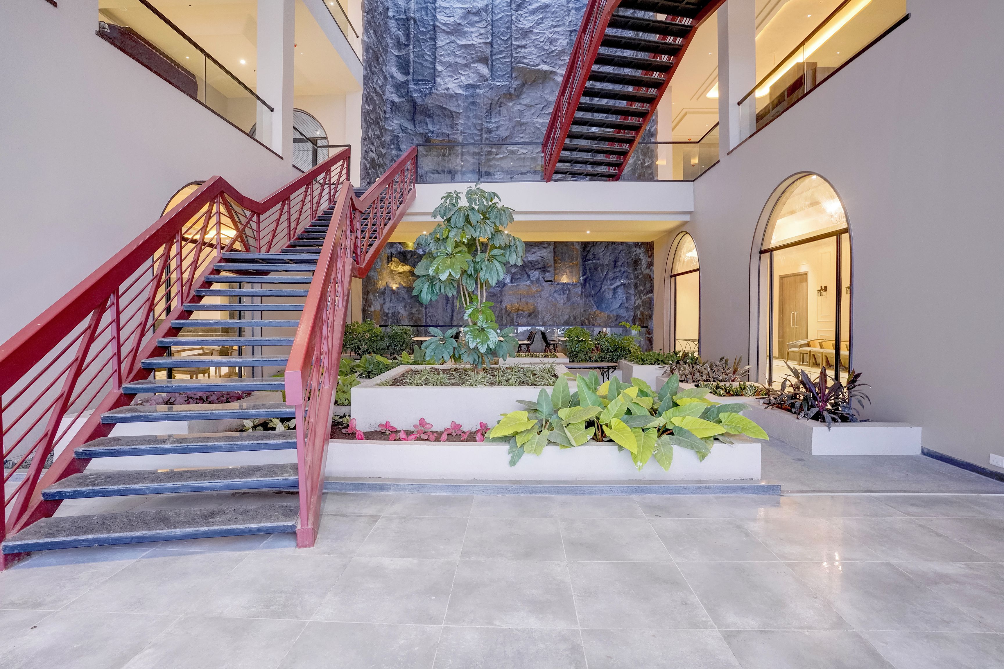 Un atrio de varios niveles con una escalera central, una pared de escalar y una variedad de plantas de interior.
