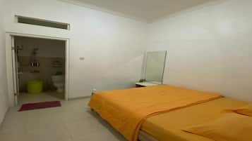 A bedroom with a bed, a mirror, a door leading to a bathroom, and a small window.