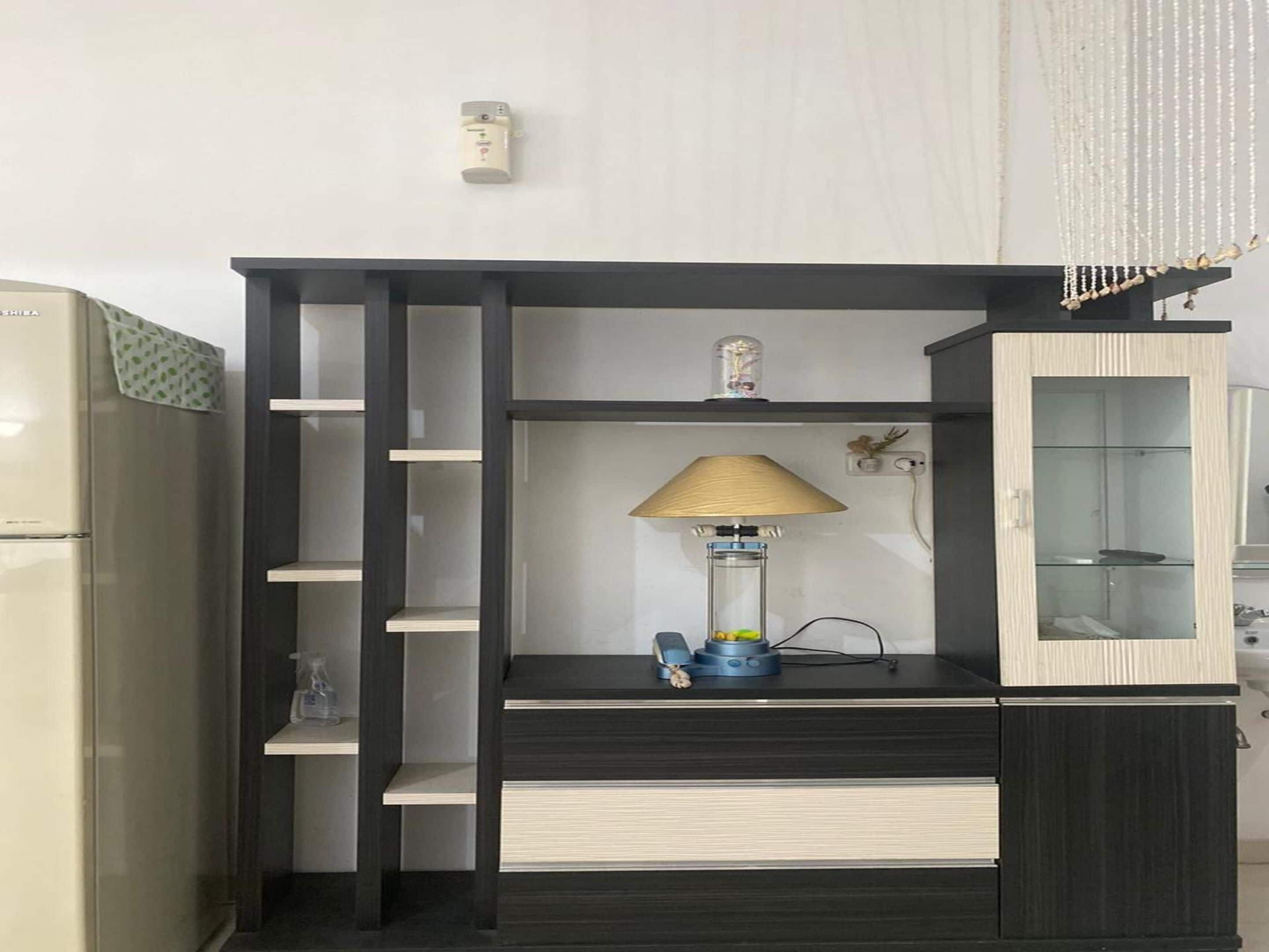 Eine Küchenzeile mit Kühlschrank, einem Schrank mit Glastür und einer Regalwand mit Lampe.