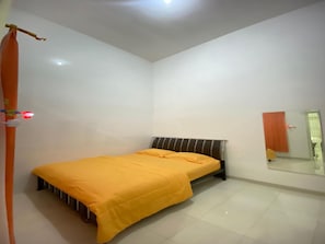 A bedroom with a single bed, a mirror, and a plain white wall. - Cozzy Villa Rizka (Batu)