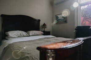 Un lit avec une tête de lit en bois, une table de chevet avec une lampe et un tableau encadré au mur.