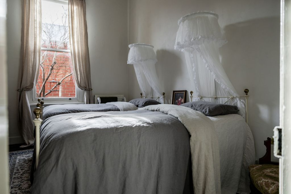 A bedroom with a large bed, a bedside table, a window with curtains, and a bedside lamp.
