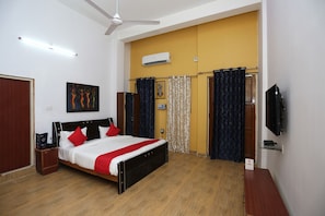 A bedroom with a bed, a ceiling fan, an air conditioning unit, a television, and a wardrobe. - Collection-O Sara Grand Near Ram (Lucknow)