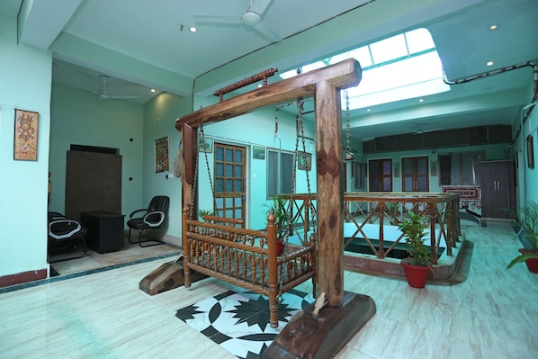 A room with a wooden swing, a tiled floor, and a ceiling fan. - Collection-O Sara Grand Near Ram (Lucknow)