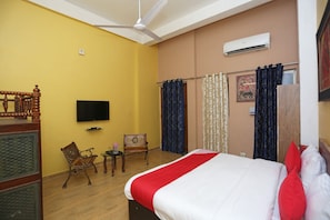 A hotel room with a bed, a television, a ceiling fan, and a window with curtains. - Collection-O Sara Grand Near Ram (Lucknow)