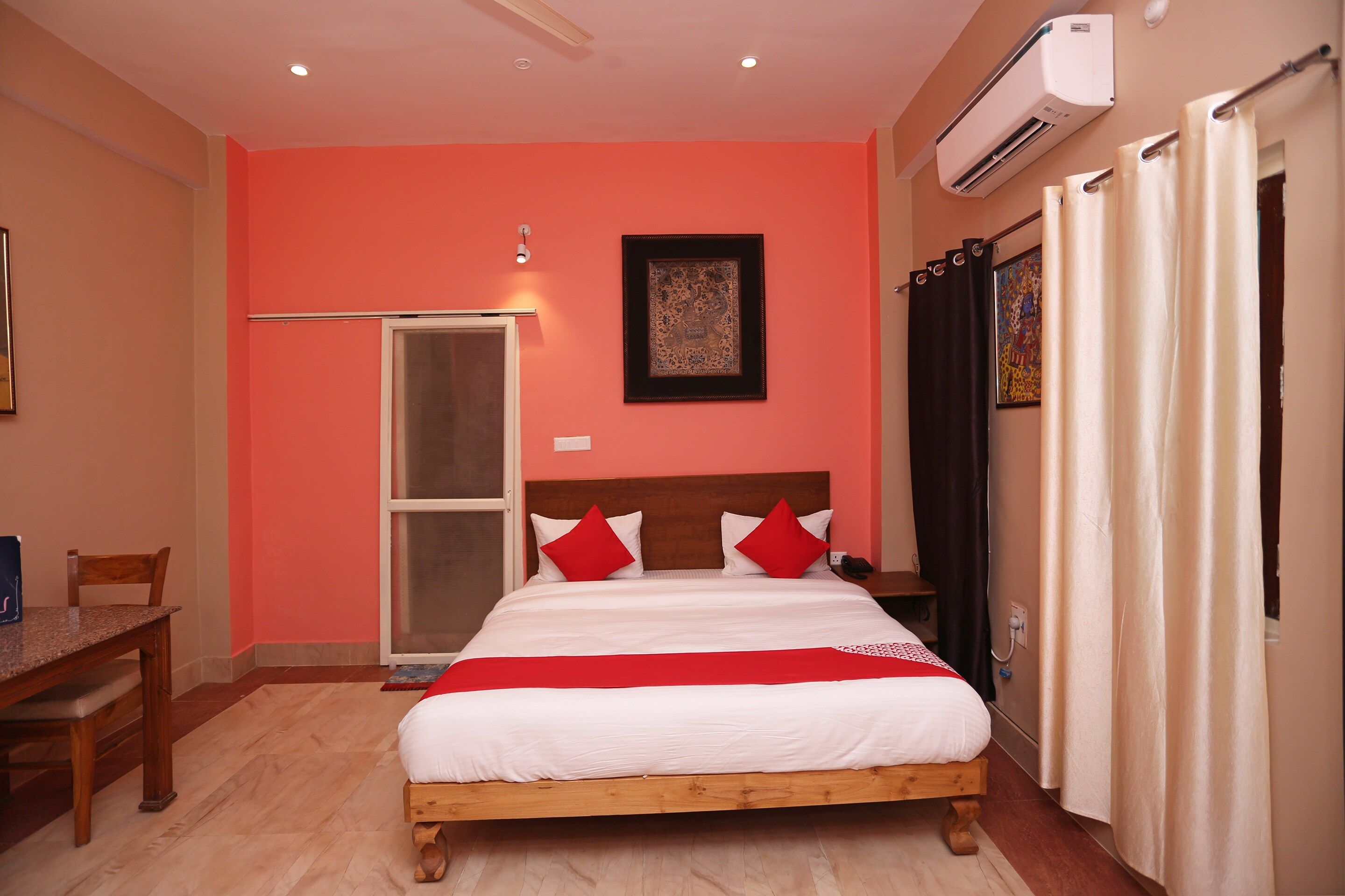 Habitación de hotel con cama, escritorio, silla, unidad de aire acondicionado y puerta.