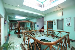 A spacious interior with a high ceiling, a central wooden staircase, and a skylight. - Collection-O Sara Grand Near Ram (Lucknow)
