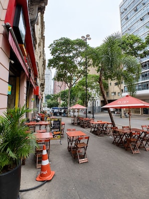 An outdoor seating area with tables and chairs, surrounded by buildings and trees. - Oscar Rodrigues 404 (São Paulo)