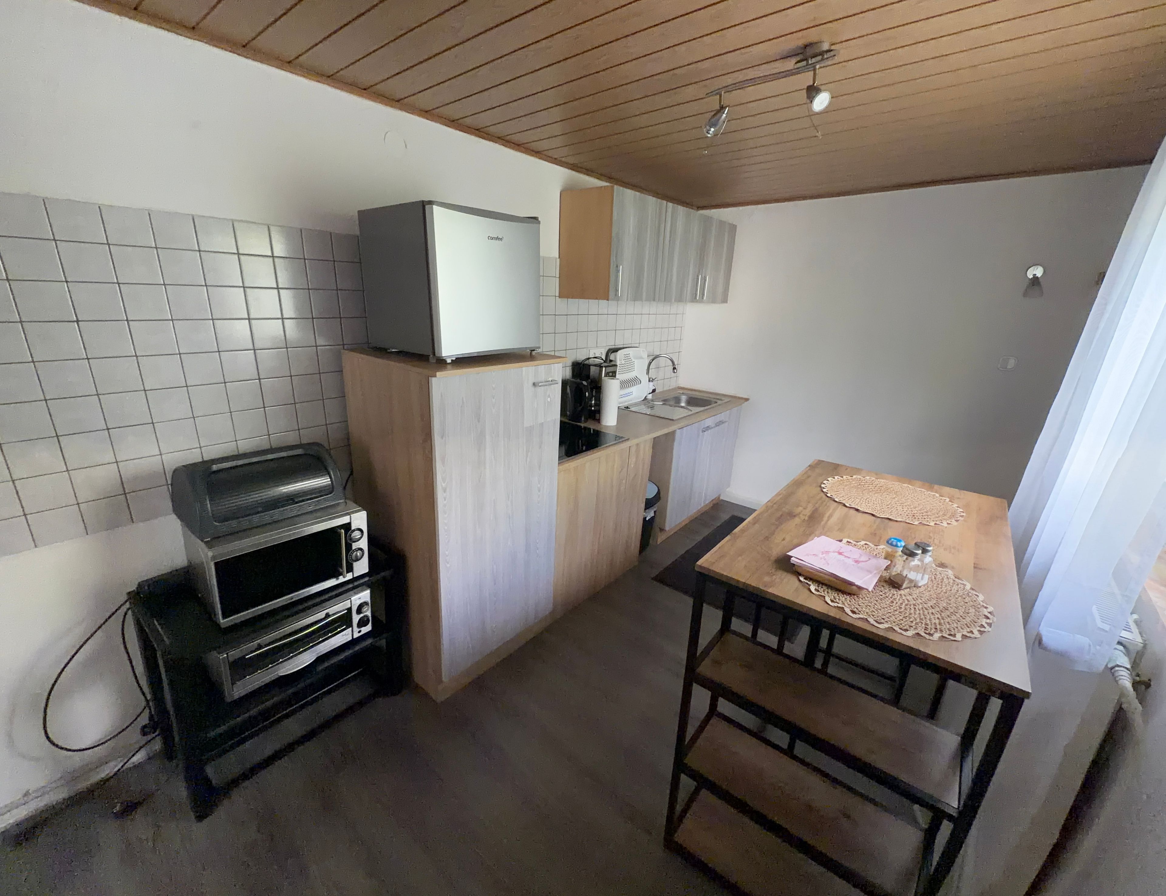 Eine kleine Küche mit integriertem Mikrowellenherd, einem Toaster und einem Spülbecken.