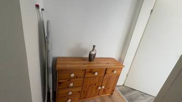 Eine hölzerne Kommode mit Schubladen, eine Vase darauf und ein Paar Ski, die an der Wand lehnen.