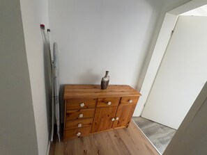 Eine hölzerne Kommode mit Schubladen, eine Vase darauf und ein Paar Ski, die an der Wand lehnen.