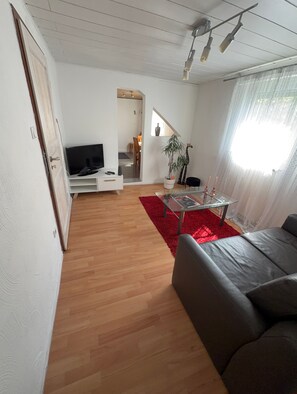 Ein Wohnzimmer mit Fernseher, einer Couch, einem roten Teppich und einer Treppe zu einem anderen Raum.