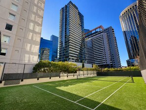 A tennis court surrounded by modern high-rise buildings. - Spectacular City Views | Large 3BR 2BA Near Crown & MCEC (Southbank)
