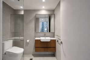 A modern bathroom with a toilet, sink, and mirror. - Spectacular City Views | Large 3BR 2BA Near Crown & MCEC (Southbank)