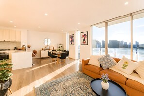 Ein modernes Wohnzimmer mit einer Küche, einem Essbereich und einem großen Fenster mit Blick auf die Stadt.