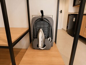 Eine kompakte Küchenzeile mit integriertem Mikrowellenherd, einem Kühlschrank und einer kleinen Bügeleinrichtung.