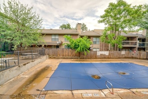 A residential area with a fenced backyard, a blue tarp covering an area, and a wooden fence. - 2-bedroom condo in soothing Dallas with Pool, AC, Wifi, Parking, Washer (Dallas)