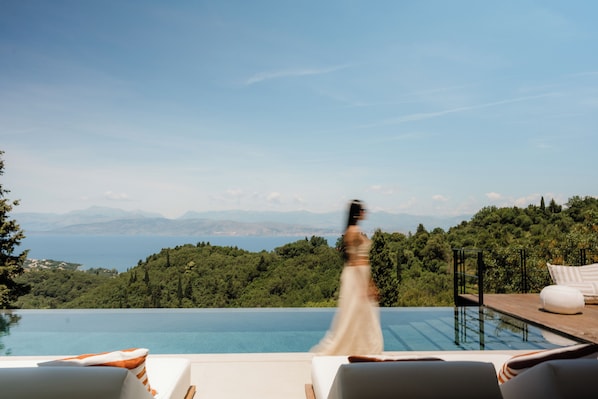 Ein Poolbereich mit Blick auf das Meer und die Berge.