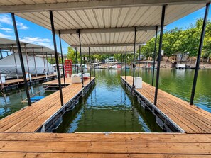 A wooden dock extending into calm water with a covered walkway overhead. - The Sunny Perch - Lakefront Home (Osage Beach)