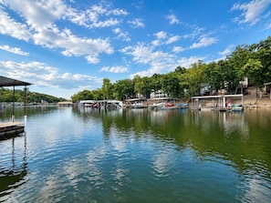A calm lake with docked boats, a wooden pier, and a clear sky. - The Sunny Perch - Lakefront Home (Osage Beach)