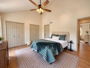 A bedroom with a bed, a ceiling fan, a bedside table, and a nightstand. - The Sunny Perch - Lakefront Home (Osage Beach)