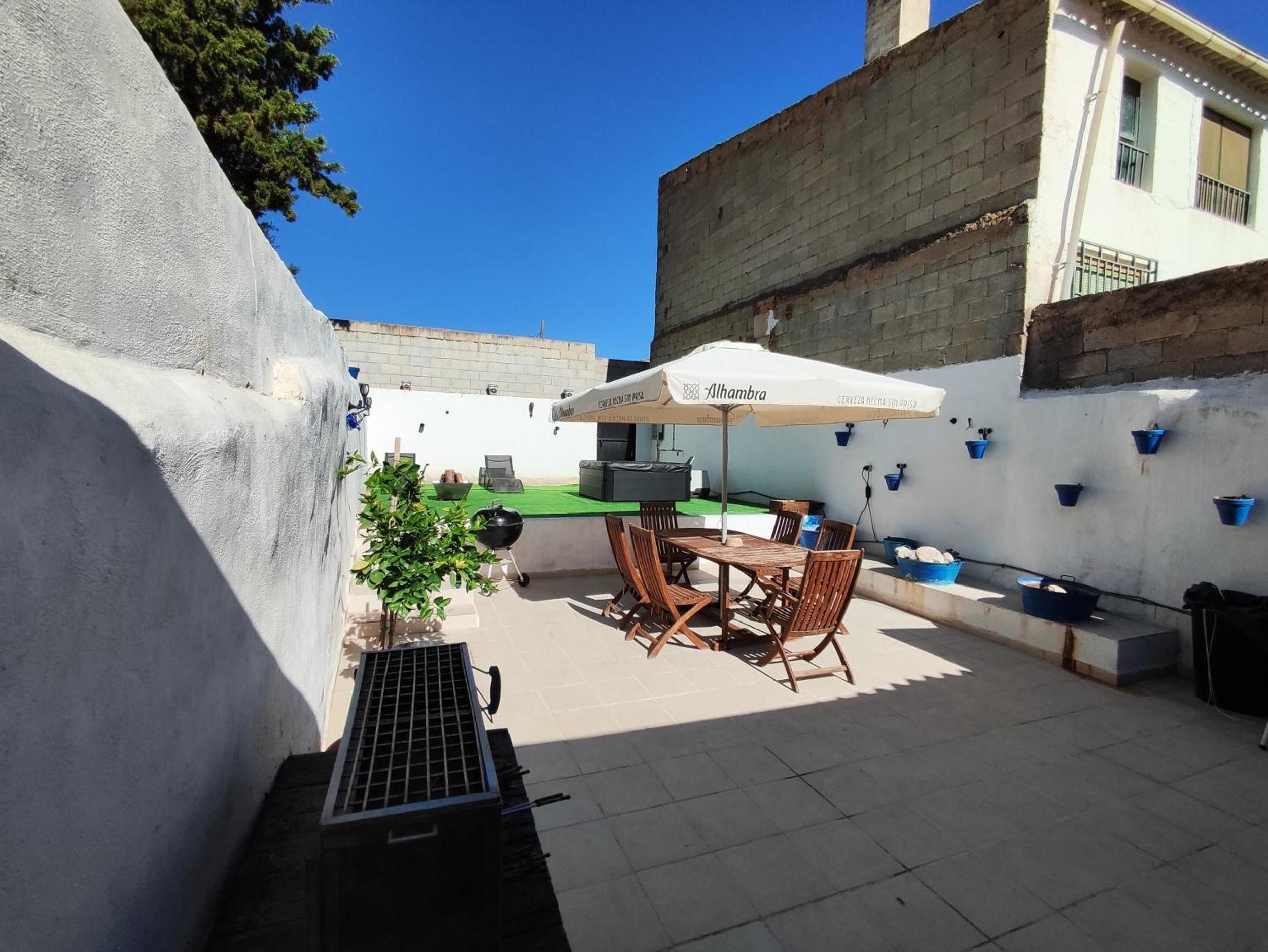 An outdoor patio with a table and chairs, a grill, and a potted plant.
