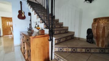 Una escalera con barandilla negra que lleva a un rellano con un armario de madera y una guitarra.