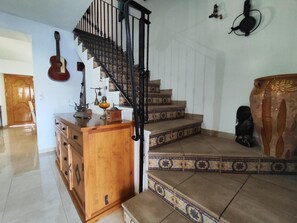 A staircase with a black railing leading to a landing with a wooden cabinet and a guitar. - Holiday Home 'Casa Rural Spa Exterior' with Mountain View, Wi-Fi and Air Conditioning (Cacín)
