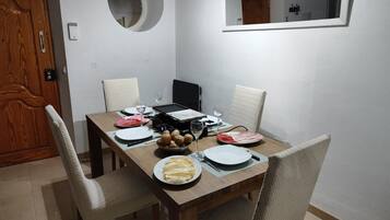 A dining area with a wooden table set for four, including plates, cutlery, and a bowl of potatoes.