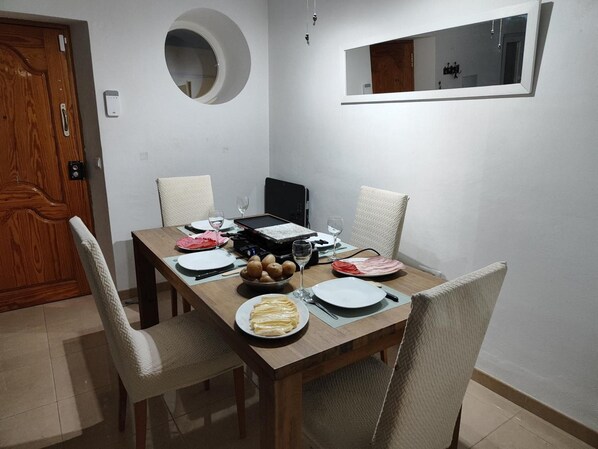 A dining area with a wooden table set for four, including plates, cutlery, and a bowl of potatoes. - Holiday Home 'Casa Rural Spa Exterior' with Mountain View, Wi-Fi and Air Conditioning (Cacín)