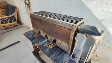 Ein tragbarer Grill mit einem Metallrost und einem Metallbehälter, aufgestellt auf einer Holzplattform.