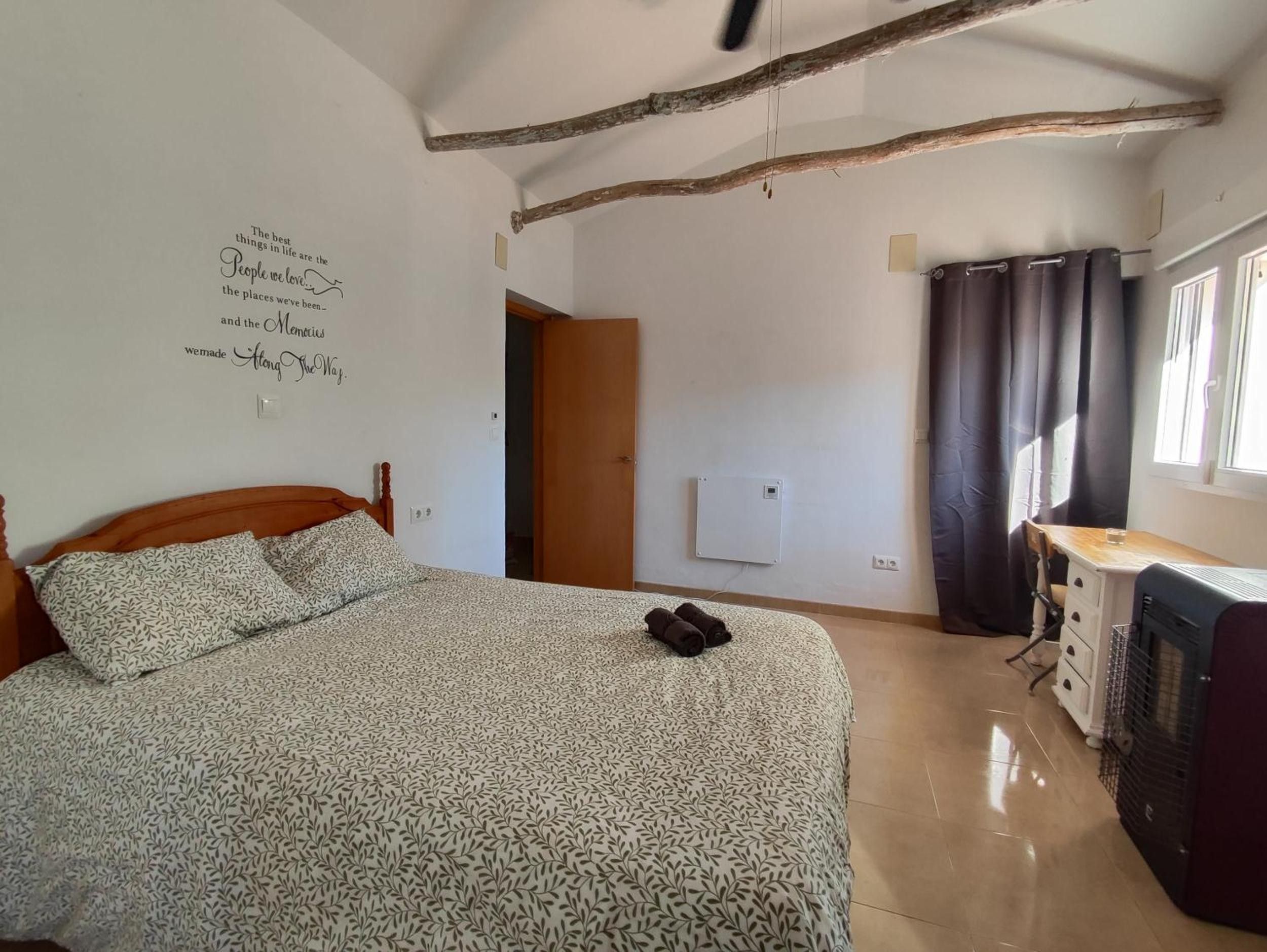 A bedroom with a bed, a desk, a radiator, and a wall with a quote.