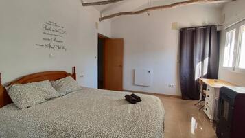 A bedroom with a bed, a desk, a radiator, and a wall with a quote.
