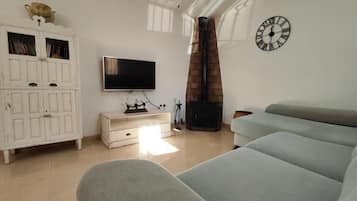 Una sala de estar con un sofá, una televisión, una chimenea y un reloj en la pared.