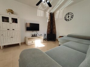 A living room with a sofa, a television, a fireplace, and a clock on the wall. - Holiday Home 'Casa Rural Spa Exterior' with Mountain View, Wi-Fi and Air Conditioning (Cacín)
