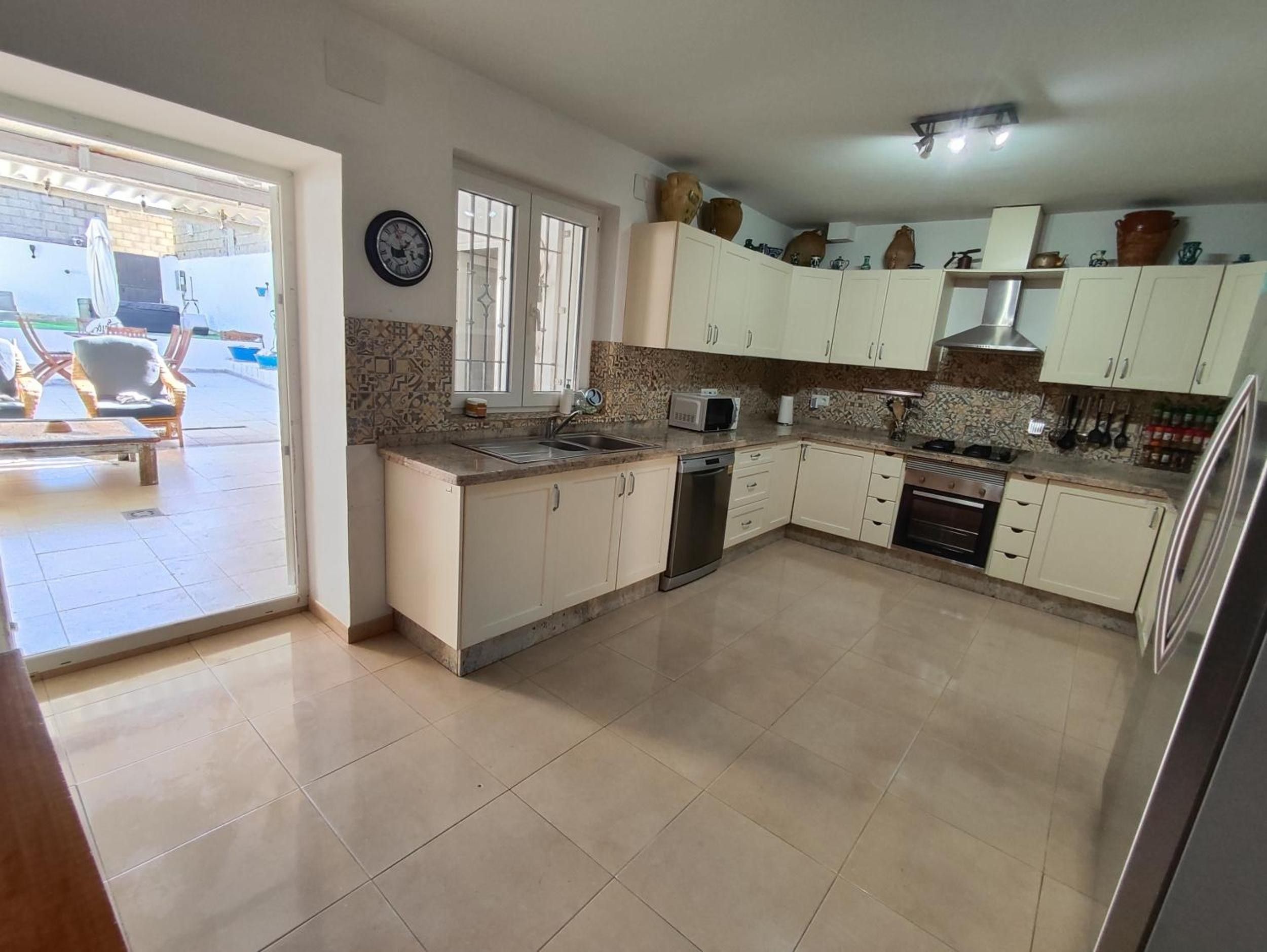 Una cocina con armarios blancos, lavavajillas, microondas y estufa.