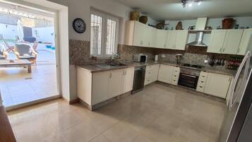 Una cocina con armarios blancos, lavavajillas, microondas y estufa.
