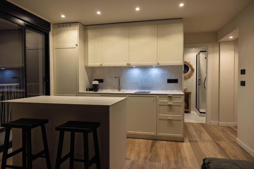 Een moderne keuken met een centraal eiland, barstoelen en een ingebouwde oven.