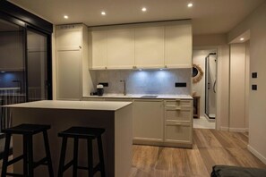Een moderne keuken met een centraal eiland, barstoelen en een ingebouwde oven.