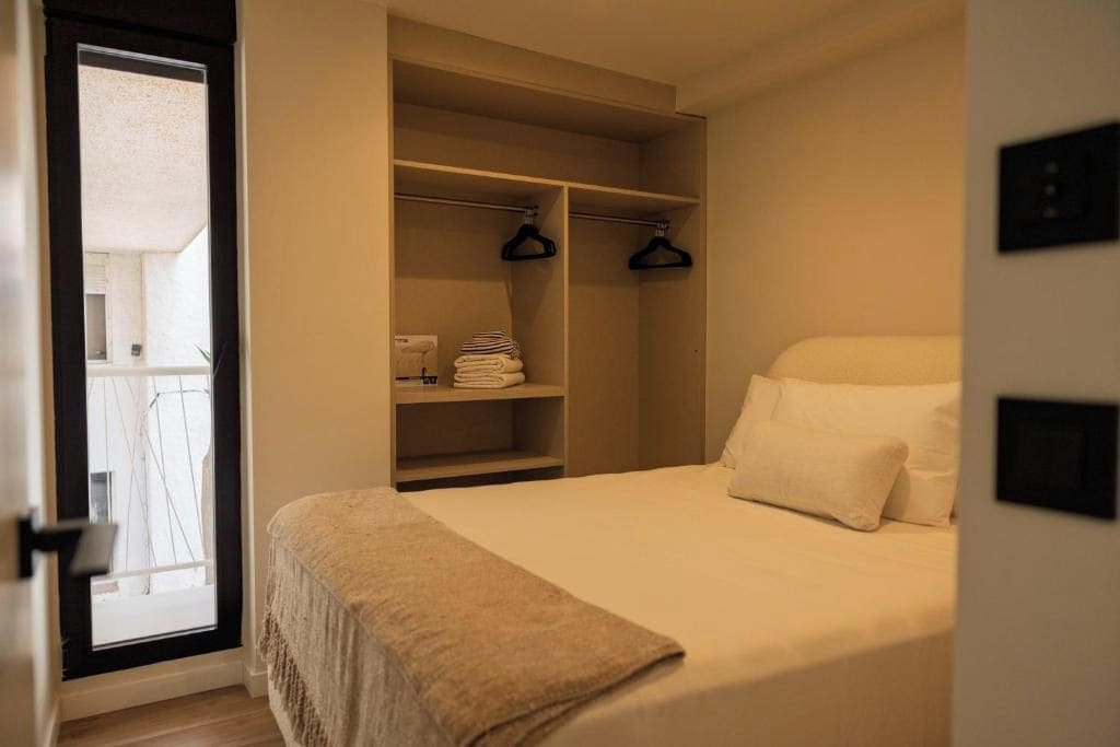 A bedroom with a bed, a wardrobe, and a door leading to a balcony.