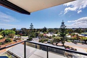 A balcony with a clear view of a residential area, including houses and trees. - Coastal Views – Mosman Park – 2BR with Balcony & Pool (Mosman Park)