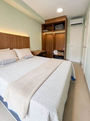 A bedroom with a large bed, a wooden wardrobe, a desk, and an air conditioning unit. - SETIN 806 (São Paulo)