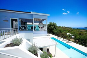 Una casa moderna con piscina, patio coperto e vista sul paesaggio.
