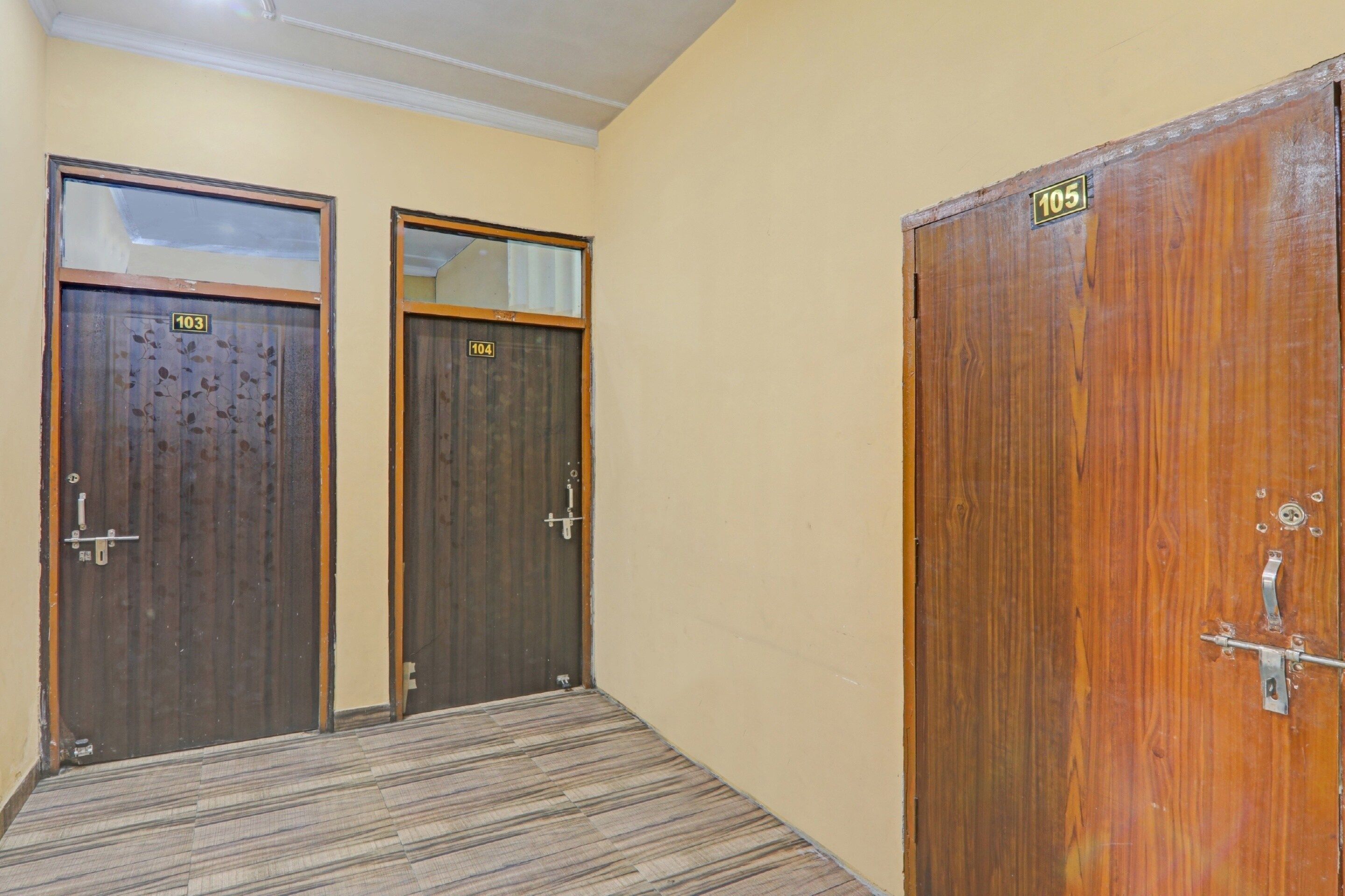 Un pasillo con dos puertas de madera, cada una con un número, que dan a una habitación.