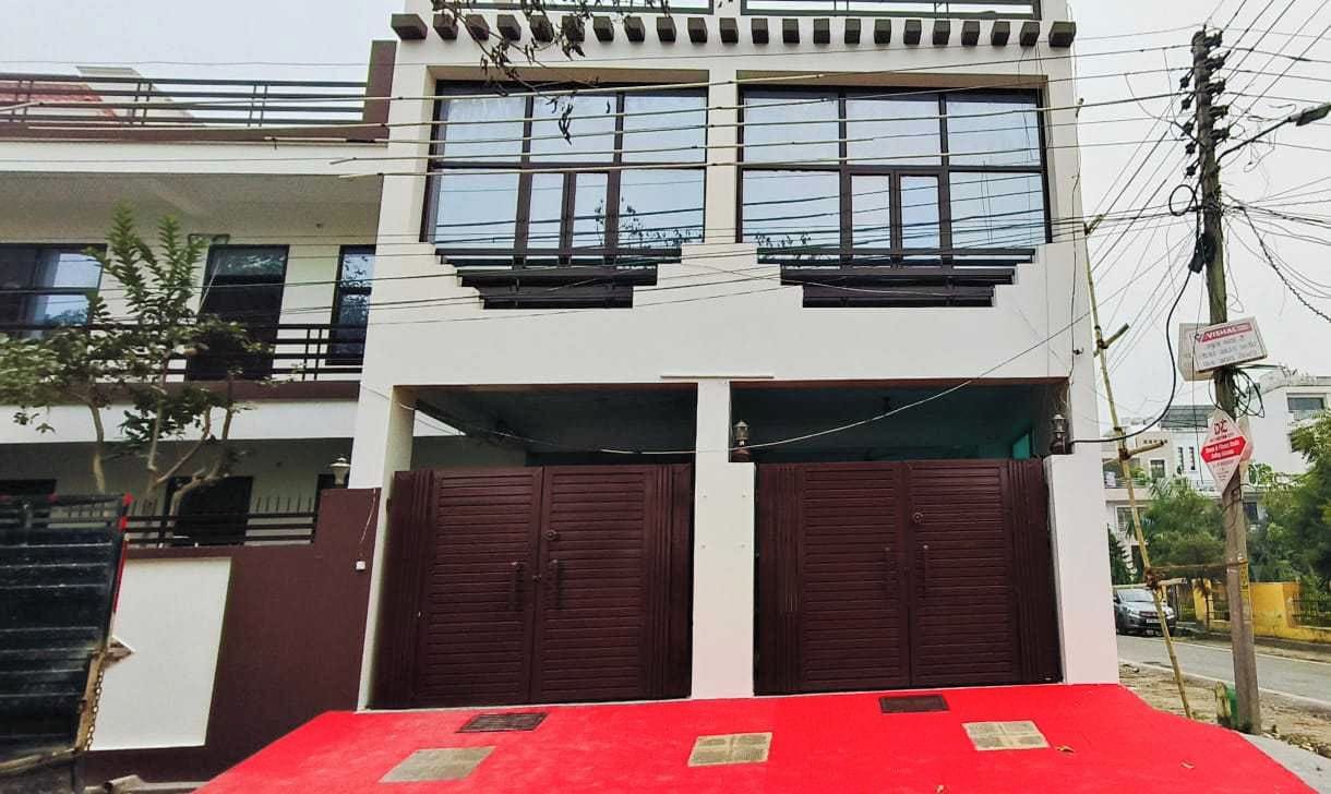 A two-story building with a red carpet leading to a gated entrance.
