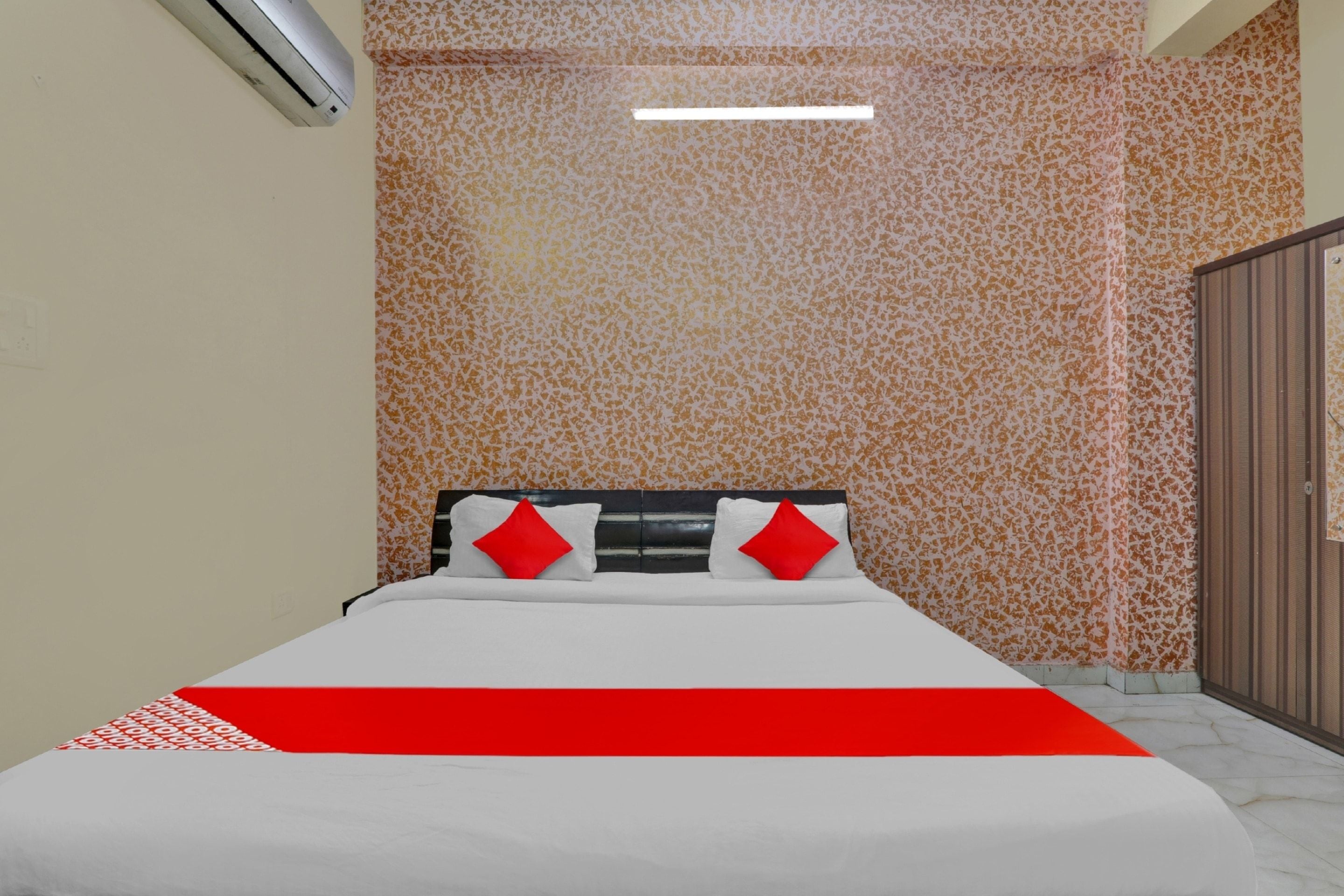 A hotel room with a bed, a wardrobe, and a patterned wall.